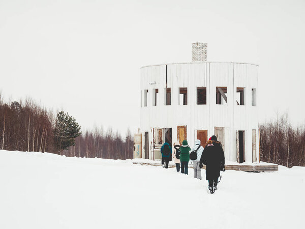 НИКОЛА-ЛЕНИВЕЦ, РОССИЯ - 15 января 2017 года. Туристы идут к деревянному арт-объекту "Ротонда" Александра Бродского. Экспонат архитектурного фестиваля "Архстояние". Зимний облачный день.