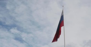 Rusya 'nın ulusal bayrağı bulutlu mavi gökyüzüne karşı rüzgarda dalgalanıyor. Gökyüzü arka planında Rus bayrağı.