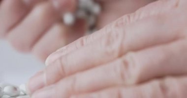 Avuç dolusu beyaz saçılma hapı. Hafif arka planda ilaçlı kapsüller.