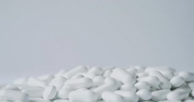 Avuç dolusu beyaz saçılma hapı. Hafif arka planda ilaçlı kapsüller.