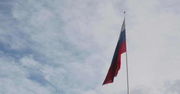 Die russische Nationalflagge weht im Wind vor blauem Himmel mit Wolken. Russische Flagge am Himmel. — Stockvideo
