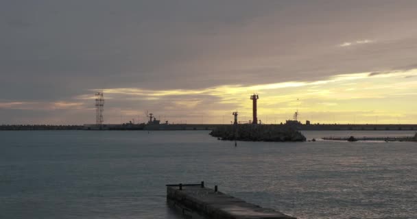 SOCHI, RUSIA - 03 de febrero de 2020. Las gaviotas y los cormoranes se sientan en el rompeolas del puerto. Faro sobre magnífico fondo del atardecer. — Vídeos de Stock