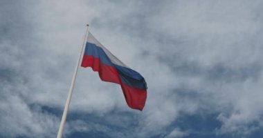 Rusya 'nın ulusal bayrağı bulutlu mavi gökyüzüne karşı rüzgarda dalgalanıyor. Gökyüzü arka planında Rus bayrağı.
