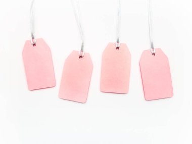 Beyaz arka planda dört pembe etiket. Fotokopi alanı olan gümüş iplikler üzerinde göz alıcı etiketler. Satış ve alışveriş sembolü. Üst manzara, düz uzanma.