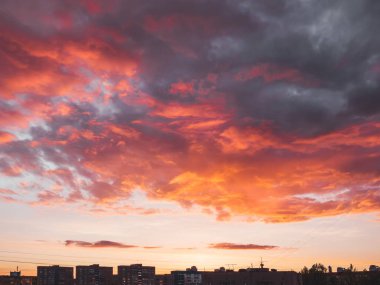Şehirde farklı şekillerde bulutlarla muhteşem bir gün batımı. Turuncu, kırmızı ve mor tüylü bulutlarla akşam gökyüzü. Renkli bulutlu manzara. 