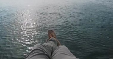 Adam sahilde dinleniyor. Deniz yüzeyinde süet spor ayakkabılı ayak manzarası. Açık hava eğlencesi.