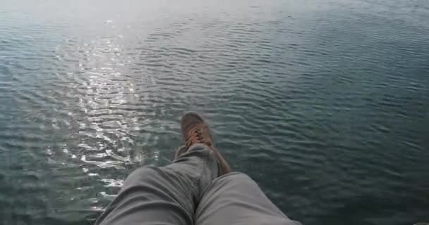 L'uomo sta riposando sulla spiaggia. Vista dei piedi in camoscio scarpe sportive sulla superficie del mare. Attività ricreative all'aperto. — Video Stock