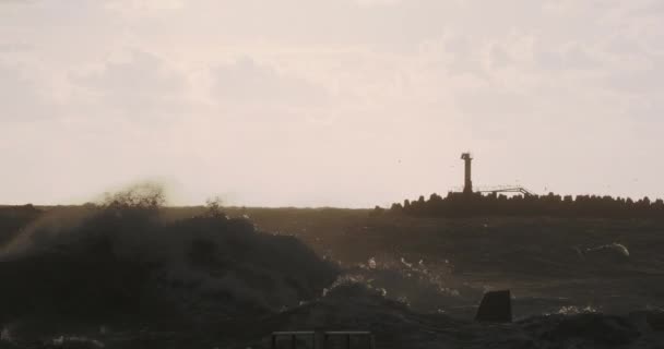 Seagulls and cormorants sit on breakwater. Lighthouse on sunset background with stormy Black sea. Port of Sochi, Russia. — Stockvideo