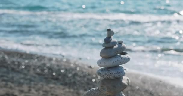 Piramide van stenen op het strand. De oogst van kiezelstenen op rotsachtige strand op zee surfen achtergrond. Door de mens gecreëerde structuur. — Stockvideo