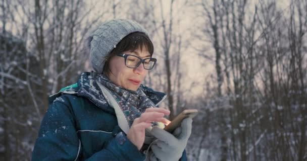 Kvinna sms:ar och bläddrar på smartphone i vinterskogen. Trådlös teknik. Online-meddelande. — Stockvideo