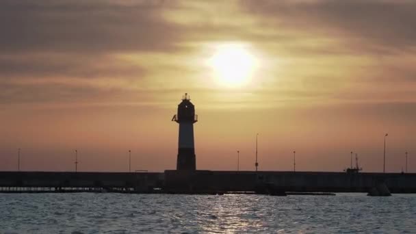 豪華な夕日の背景に灯台のシルエット。ソチの港、ロシア. — ストック動画