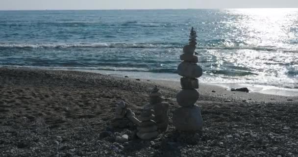 Steinpyramide am Strand. Kieselsteinhaufen am felsigen Strand auf Meeresbrandung Hintergrund. Menschengemachte Struktur. — Stockvideo
