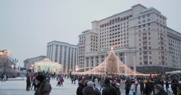 MOSKAU, RUSSLAND - 08. Januar 2021. Menschen spazieren um den geschmückten Weihnachtsbaum vor dem Four Seasons Hotel am Manezhnaya Platz. — Stockvideo