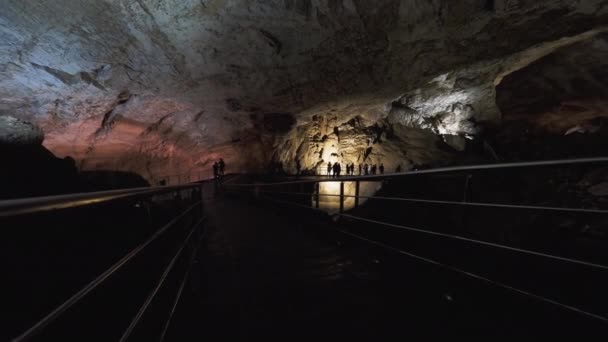 Los turistas caminan en la cueva de New Athos. Siluetas de personas en Novoafonskaya, Novy Afon o Nueva Cueva Afon. Abjasia. — Vídeo de stock