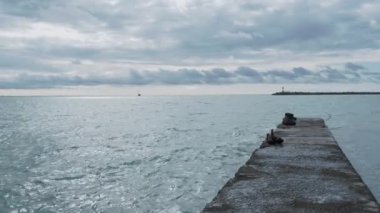 Bulutlu arka planda deniz fenerinin silueti. Soçi Limanı, Rusya. Beton kırma suyundan görüntü.