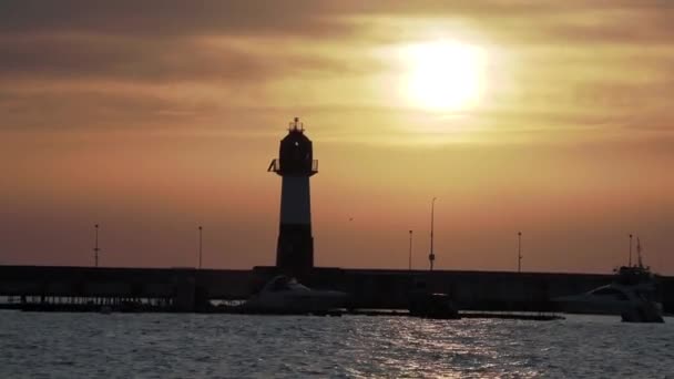 豪華な夕日の背景に灯台のシルエット。ソチの港、ロシア. — ストック動画