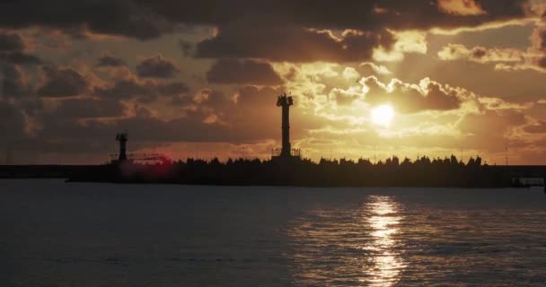 Martılar ve karabataklar dalgakıranların üzerinde otururlar. Muhteşem günbatımı arka planında deniz feneri. Soçi Limanı, Rusya. — Stok video