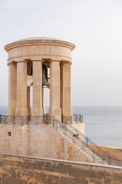 Kuşatma Çanı Savaş Anıtı bulutlu gökyüzü ve yüzey Akdeniz arka planında. Valletta, Malta 'da mimari dönüm noktası.