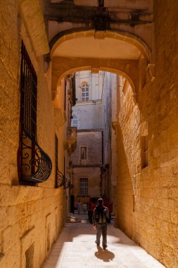 MDINA, MALTA - 18 Şubat 2010. Turistler Mdina 'nın antik dar sokaklarında yürüyorlar. Eski moda fenerleri ve balkonları olan eski binalar..