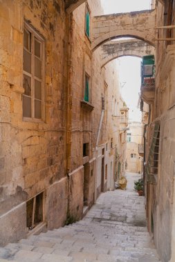 Valletta, Malta 'da eski dar bir cadde. Eski moda fenerleri ve balkonları olan kireçtaşı binalar. Asfalt gibi birçok basamaklı merdiven.