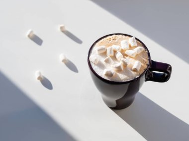 Marşmelovlu kapuçino bardağının üst görüntüsü. Kahve fincanı ile geometrik minimalist arka plan. Işık, gölge ve süt köpüklü sıcak içecek..