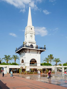 KEMER, TURKEY - 13 Mayıs 2018. Yerel halk ve turistler Atatürk Bulvarı 'nın mimari simgesi olan Beyaz Saat Kulesi' nin yakınında yürüyorlar..