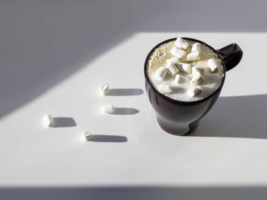 Marşmelovlu kapuçino bardağının üst görüntüsü. Kahve fincanı ile geometrik minimalist arka plan. Işık, gölge ve süt köpüklü sıcak içecek..