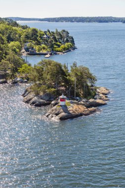 İsveç 'in başkenti Stockholm yakınlarındaki adada küçük kırmızı ve beyaz bir deniz feneri. Güneşli bir günde gemilerin seyrüsefer için yapılan bina manzarası. İskandinavya 'da yaz tekne gezisi.