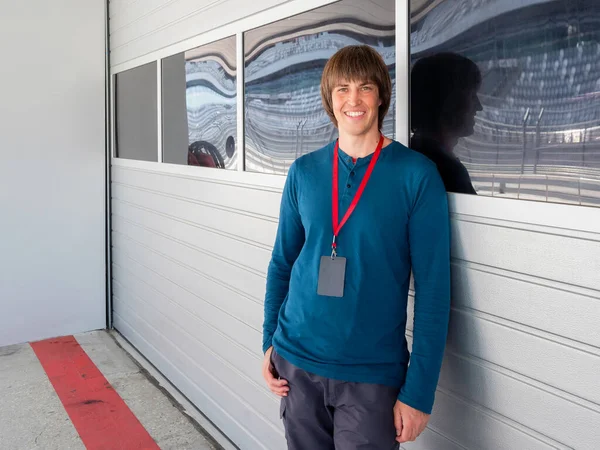 Kırmızı kurdeleli, geniş gülümseyen adam Autodrom 'da pit lane' de kalıyor. Spor araba yarışı. Özel pistte spor müsabakası.