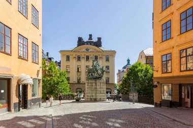 STOCKHOLM, İSVEÇ - 6 Temmuz 2017. Turistler, Bernt Notke 'un Aziz George ve Ejderha heykelinin bronz kopyası etrafında dolaşıyorlar. Kopmantorget veya Merchant Meydanı 'ndaki antik binalar.