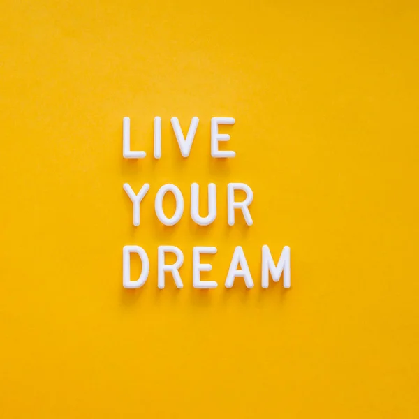 Live your dream. Motivating and inspiring phrase on bright yellow background. Top view on lifting spirit message. Creative rise.