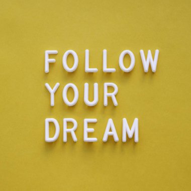 Follow your dream. Motivating and inspiring phrase on bright yellow background. Top view on lifting spirit message. Creative rise. clipart