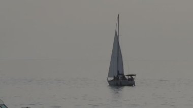 Yolcularla birlikte yelkenli yatının silueti. Gün batımında deniz gezisi. İnsanlar modern yatla deniz yoluyla seyahat ederler..