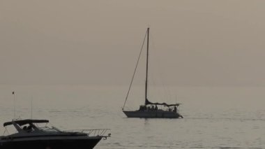 Yolcularla birlikte yelkenli yatının silueti. Gün batımında deniz gezisi. İnsanlar modern yatla deniz yoluyla seyahat ederler..