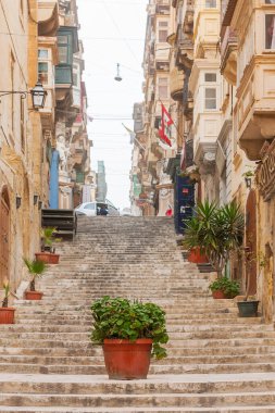 VALLETTA, MALTA - 20 Şubat 2010. Eski moda balkonları ve kaldırımı olan antika binalar. Valletta 'da vazolarla ve çiçek saksılarıyla büyüyen eski yaya sokakları.