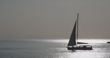 Yolcularla birlikte yelkenli yatının silueti. Gün batımında deniz gezisi. İnsanlar modern yatla deniz yoluyla seyahat ederler..