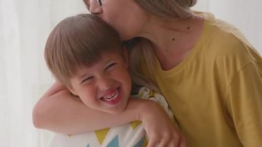 Anne, oğlunun saçını evde kesiyor. Yeni normal. Oğlan örtülü oturur ve makasla oynar. Yaşam tarzı, kişisel bakım..