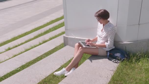 안경을 쓴 사업가는 시립 공원에서 노트북을 가지고 일한다. 여름에 프리랜서들을 위한 옥외 작업장. — 비디오