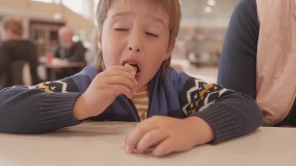 Mały chłopiec je lody w centrum handlowym. Słodki dzieciak z pysznym zimnym deserem wafla stożka z bitą śmietaną. — Wideo stockowe