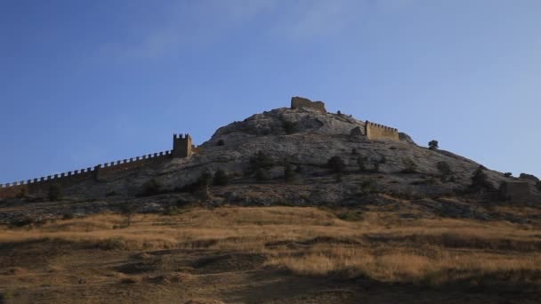 Bottom view of ancient Genoese fortress in Sudak town. Historic architectural landmark at sunset. Crimea. — Stock Video