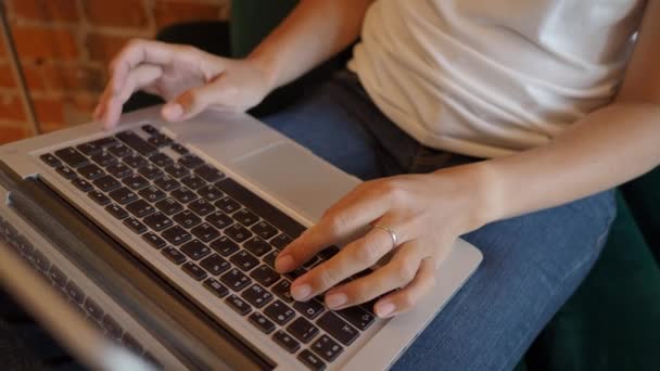 Mulher trabalha remotamente em café com paredes de tijolo vermelho. Tipos femininos no teclado do laptop. Co-working center com loft interior estilo. Local de trabalho independente. — Vídeo de Stock