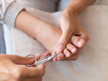 Anne çocuğunun ayak parmaklarıyla tırnak kesiyor. Evde sağlık hizmeti prosedürü. Çocuk için pedikür.