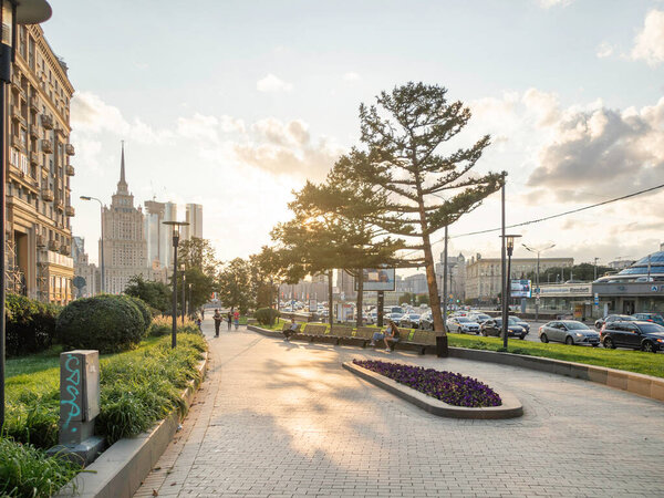 MOSCOW, RUSSIA - August 22, 2021. People are walking on alley along Novy Arbat street. Summer sunset in modern capital with lawns and skyscrapers.
