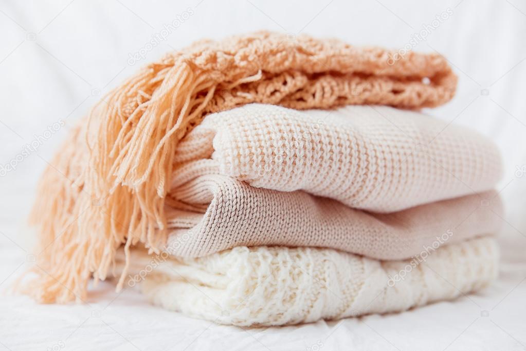 Pile of beige woolen clothes on a white background. Warm knitted