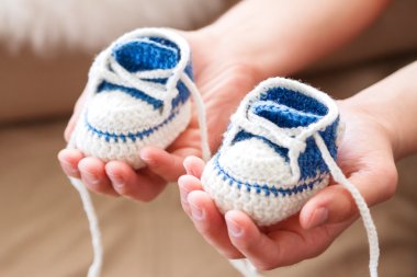 Küçük bebek ayakkabıları. Handknitted ilk spor ayakkabı erkek ya da kız için. Baba'nın elinde el yapımı patik tığ işi. Yeni Örgü ayakkabı baba sunar.