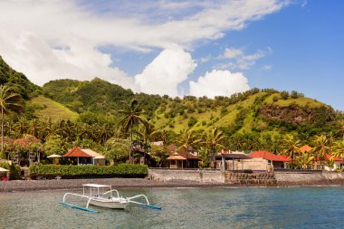 Coast of Bali - sea, boats, palms and bungalow. Bali island, Indonesia.