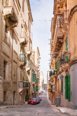 Valletta, Malta - Şubat 20, 2010. Eski sokak Valletta, Malta için. Eski moda balkon, oyma taş duvarlar ve kemerler ile dar sokak.