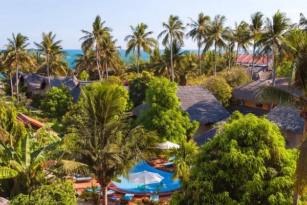 View on hotel by the sea from above. Bungalows, swiming pool, palm trees and chaise lounges. Vietnam.