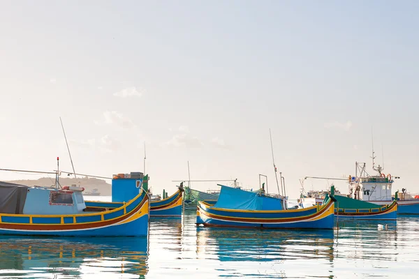 Typické barevné lodě - středomořské tradiční rybářské vesnice v jihovýchodní části Malty. Brzy zimní ráno v Marsaxlokku, Malta. — Stock fotografie