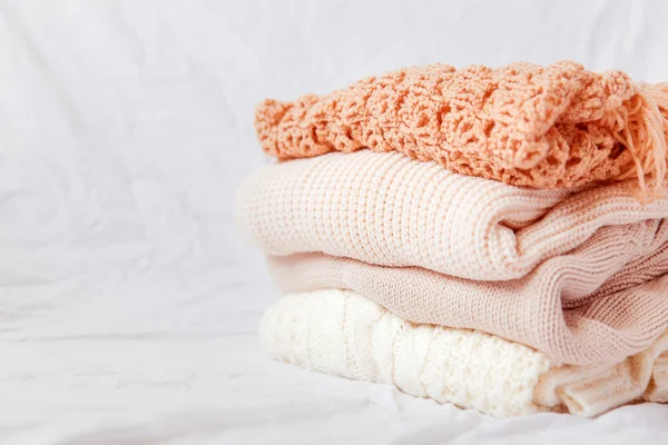 Pile of beige woolen clothes on a white background. Warm knitted sweaters and scarfs are folded in one heap. — Stock Photo, Image